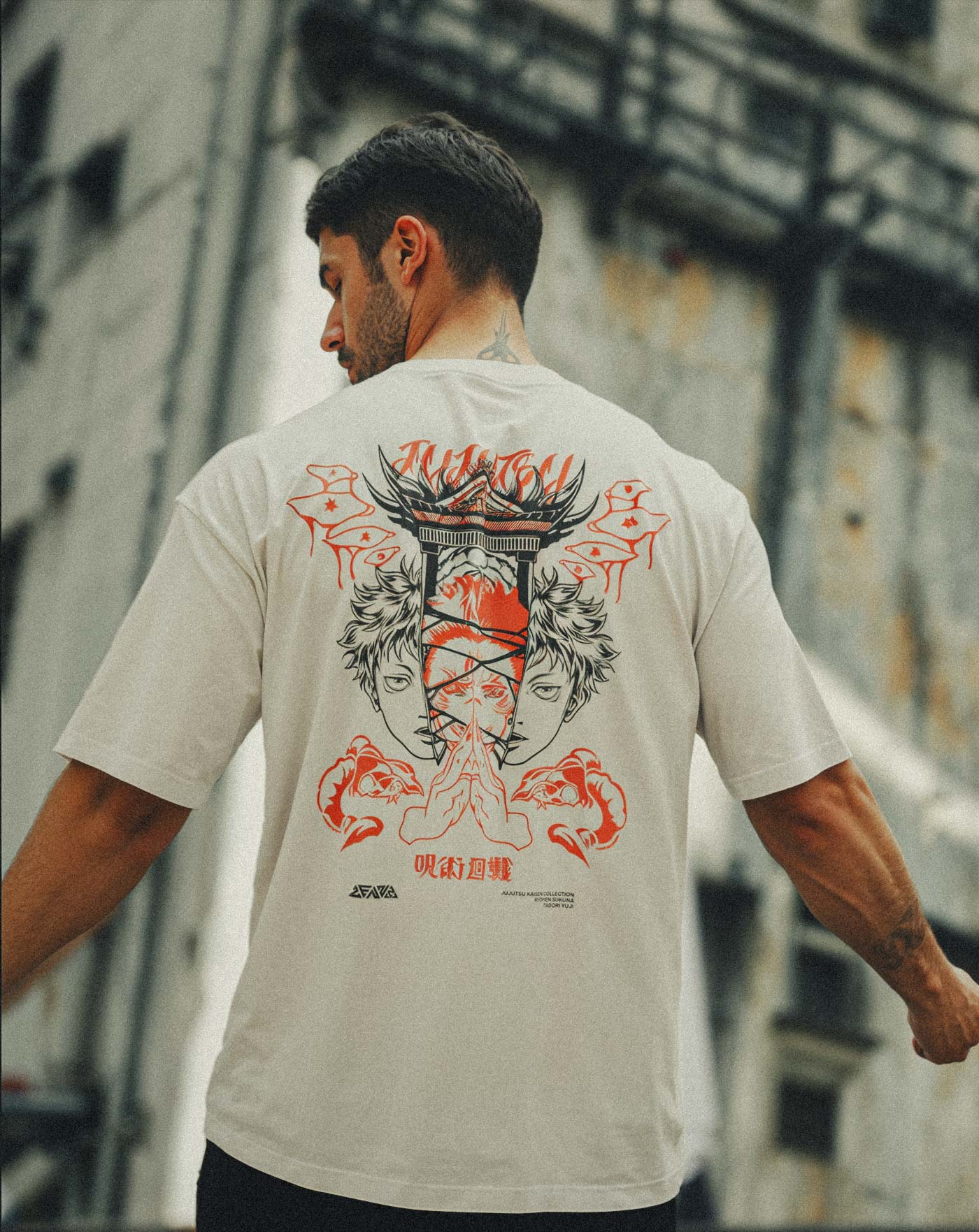 Man wearing a beige anime-inspired streetwear t-shirt featuring a bold red and black back graphic of twin faces and hand symbols, relaxed oversized fit from Torazen’s bestselling collection.