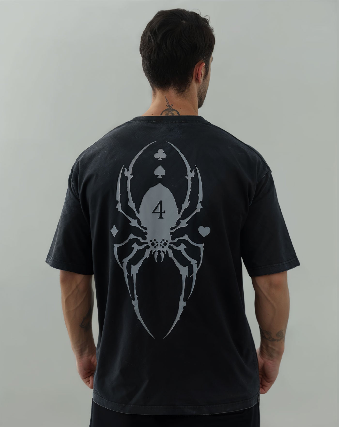 Man wearing a black vintage washed anime-inspired streetwear t-shirt featuring a large spider and card suit graphic on the back, relaxed oversized fit from Torazen’s Bungee Gum 2-Sided Vintage Tee.