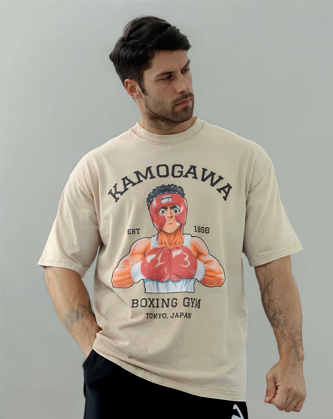 Man wearing a beige vintage washed anime-inspired streetwear t-shirt featuring a bold boxing gym graphic design, relaxed oversized fit from Torazen’s Ippo Spar Vintage Tee.