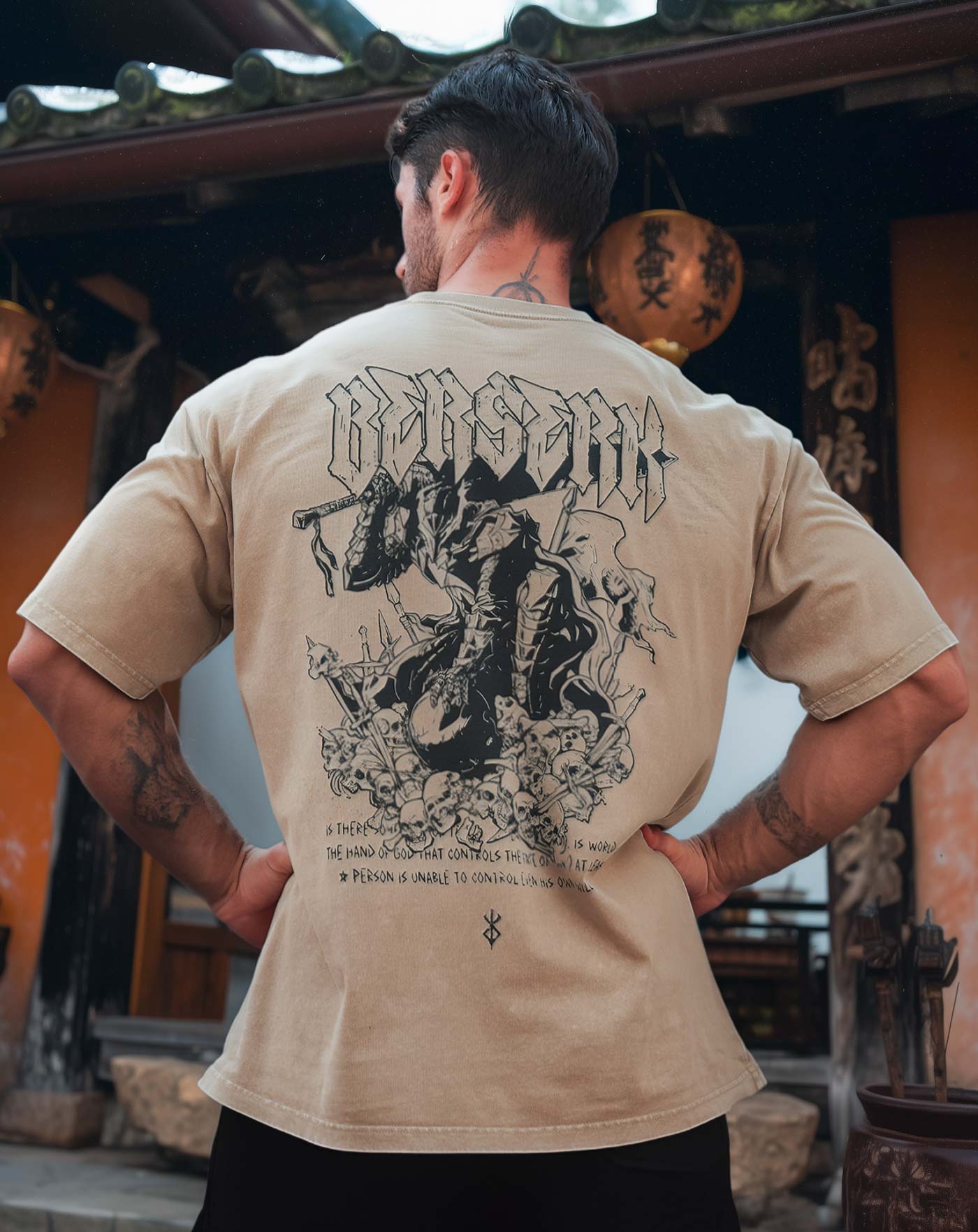 Man wearing a beige vintage washed anime-inspired streetwear t-shirt featuring a detailed warrior and skull back graphic, relaxed oversized fit from Torazen’s Berserk Mode tee.