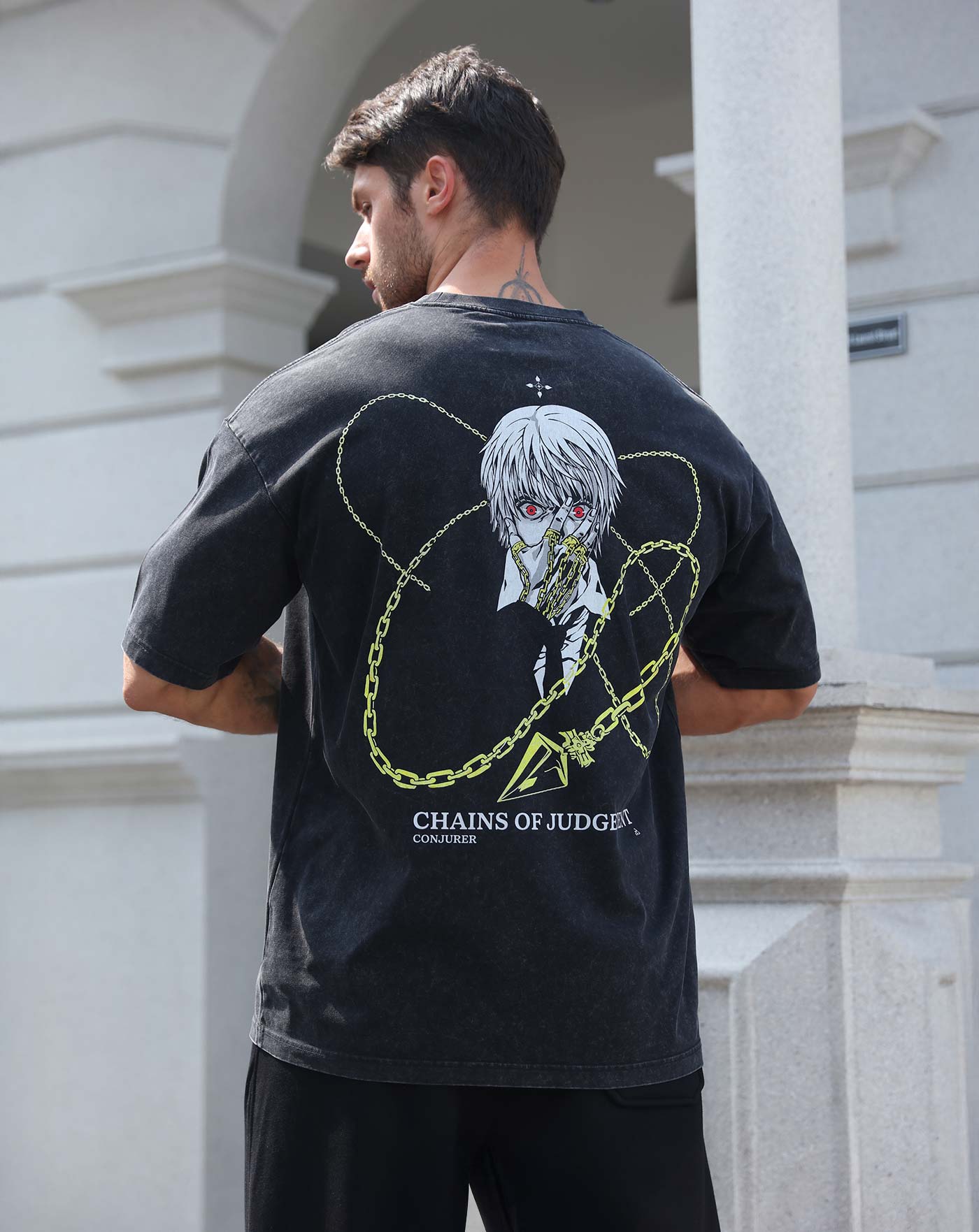 Man wearing a black vintage washed anime-inspired streetwear t-shirt featuring a silver-haired character with gold chain graphics on the back, relaxed oversized fit from Torazen’s Chains of Judgment tee.