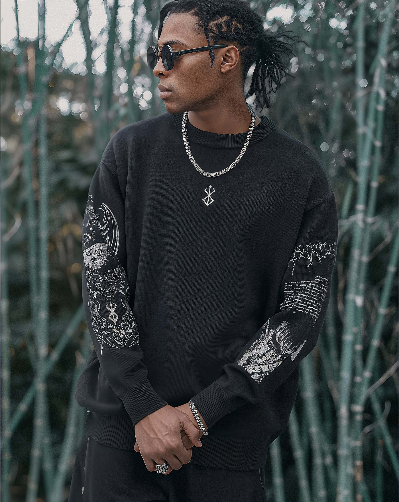 Man wearing a black anime-inspired streetwear sweatshirt featuring intricate sleeve graphics and a minimal front design, styled with chain and sunglasses from Torazen’s Dark Armor collection.
